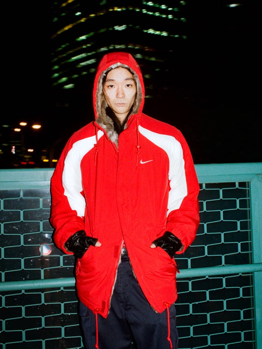 Supreme × Nikeの公式ルック。白い切り替えとフード周りのファーを備えた赤いパーカの着用写真
